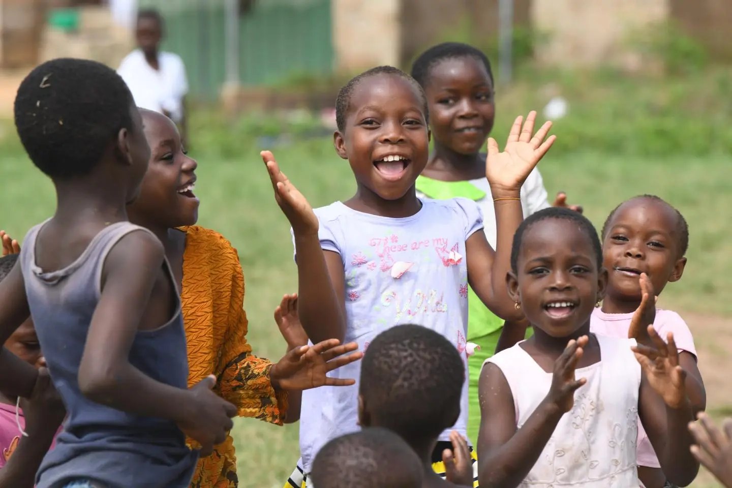 Children smiling and waving outdoors